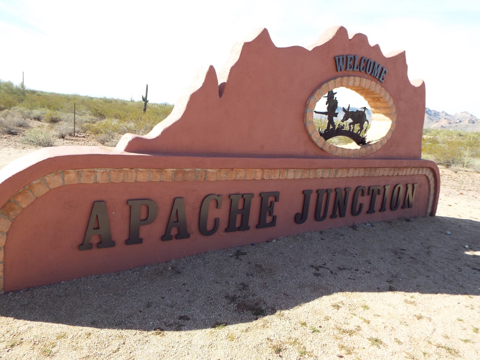 Welcome to Apache Junction road sign with prospector and burro cutout